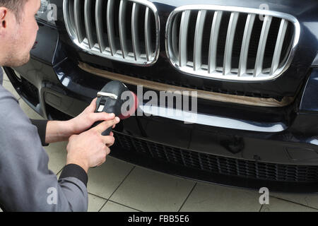 Le travailleur polit une voiture avec le pare-choc de bord outil électrique. Close up Banque D'Images