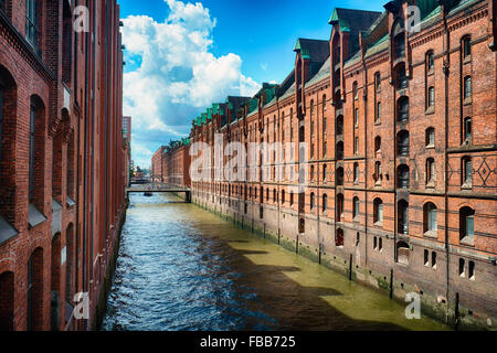 Vue sur une rangée d'entrepôts en brique rouge le long d'un canal, Speicherstadt, Hambourg, Allemagne Banque D'Images