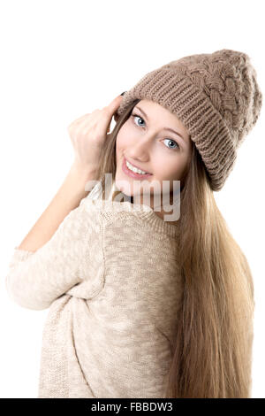 Beautiful happy smiling teenage girl à essayer des vêtements tricotés beige sur hat, isolé Banque D'Images