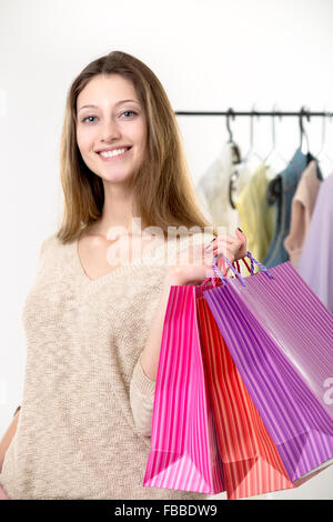 Souriante jeune femme heureux après l'achat de biens, shopping, transportant des sacs de papier coloré Banque D'Images