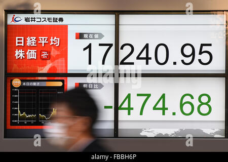 Tokyo, Japon. 14 janvier, 2016. Un homme passe devant une pancarte indiquant le prix des actions japonaises le 14 janvier 2016 à Tokyo, Japon. En dépit des signes de reprise le mercredi, le Nikkei 225 Stock Average a terminé la journée en baisse de 2,7  % à 17 240,95. D'autres marchés à travers l'Asie ont également subi le pétrole a chuté en dessous de 30 dollars le baril et les inquiétudes persistent au sujet de la croissance chinoise. Credit : Ito Shingo/AFLO/Alamy Live News Banque D'Images