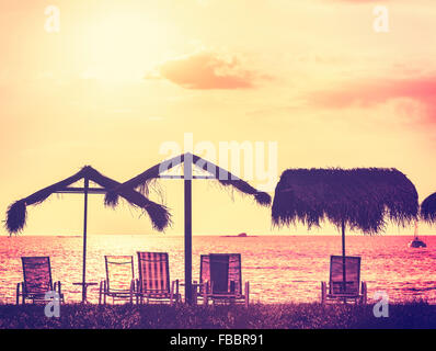 Tons Vintage chaises et parasols de plage au coucher du soleil, des vacances. Banque D'Images