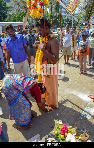 Bombay Mumbai Inde Macchimar Nagar Village de pêcheurs festival hindou de Thaipusam en l'honneur du Seigneur Shiva. Une femme se penche pour demander la bénédiction d'un homme qui prendra part au festival et pierce son corps avec crochet Banque D'Images