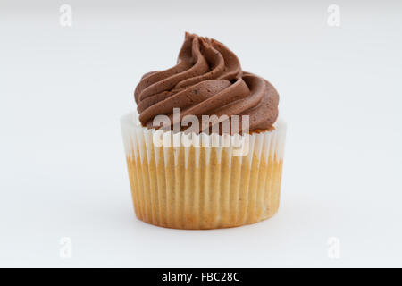 Un petit gâteau au chocolat avec glaçage tourbillonné sur un fond blanc. Banque D'Images
