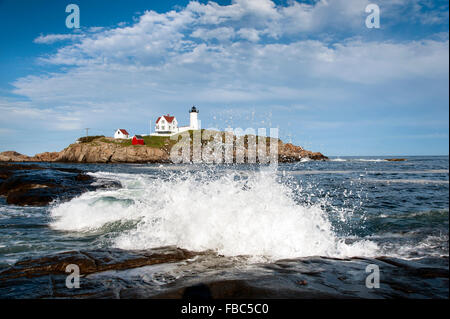 Vagues se briser sur les rochers par le phare de Nubble dans le Maine. Les vagues semblent refléter de manière unique les nuages au-dessus de la balise. Banque D'Images