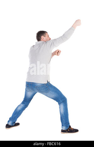 Vue arrière de l'homme debout tirant une corde depuis le haut ou s'accrocher à quelque chose. guy regarder. Vue arrière Vue arrière. collection les gens de personne. Plus isolé sur fond blanc. les jambes homme tire Banque D'Images
