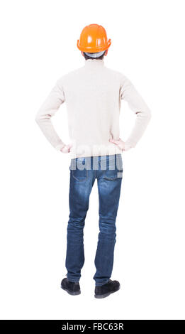 Un ingénieur de construction de stands casque. Jeune homme debout. Vue arrière Vue arrière. collection les gens de personne. Plus isolé sur fond blanc. Les mains sur les hanches d'ingénieur à l'avant. Banque D'Images