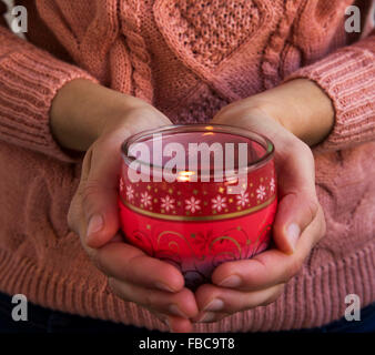 Les mains tenant Parfum Noël bougie allumée Banque D'Images