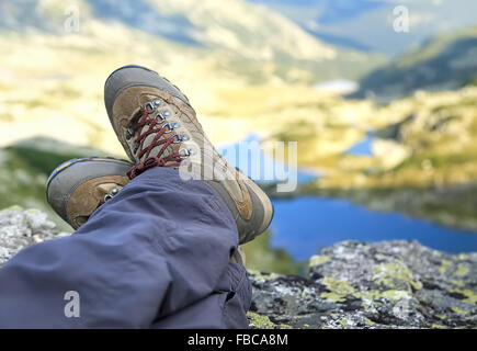 Bottes femme Hiker Resting sur sommet de montagne avec des lacs de montagne dans l'arrière-plan Banque D'Images