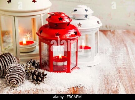 Lanternes de Noël vintage avec des bougies et de cônes dans la neige sur table en bois Banque D'Images