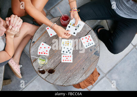 Vue du haut de trois jeunes amis Cartes à jouer au café. Les jeunes gens jouer au jeu de cartes au café. Banque D'Images