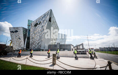 Les utilisateurs de Segway passer Belfast Titanic emblématiques de l'immeuble. Banque D'Images