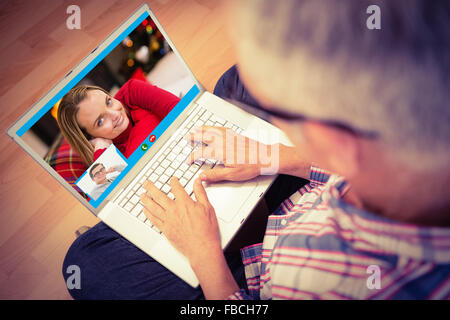Image composite de l'homme à l'aide d'ordinateur portable tout en étant assis sur le plancher à la maison Banque D'Images