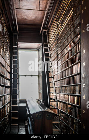 Bibliothèque des échelles pour atteindre les livres sur des étagères supérieures à Trinity Library Dublin. Banque D'Images