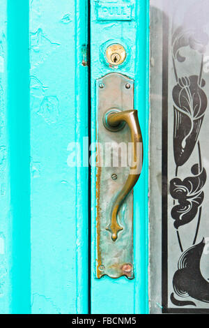 Une poignée en métal vintage sur une porte en bois peint turquoise Banque D'Images