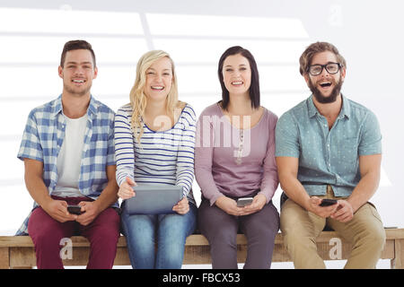 Image composite de portrait of smiling business people holding gadgets électroniques Banque D'Images