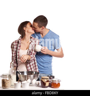 Homme affectueux baiser sa petite amie tout en coupant le pain pour le petit-déjeuner dans la cuisine Banque D'Images