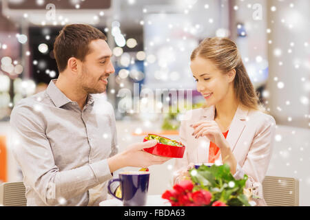 Couple heureux avec boite de chocolat et roses en mall Banque D'Images