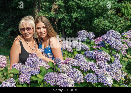 Deux femmes de générations différentes, debout près de fleurs d'hortensias. Mère et fille Banque D'Images