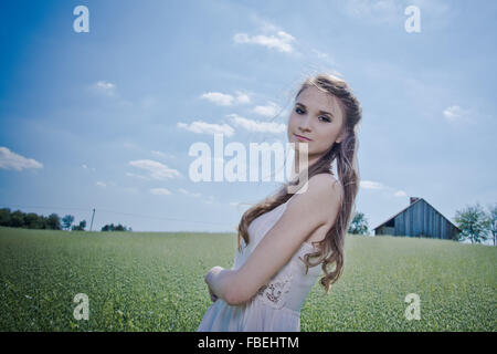 Portrait of Young Woman Standing Against Sky On Grassy Field