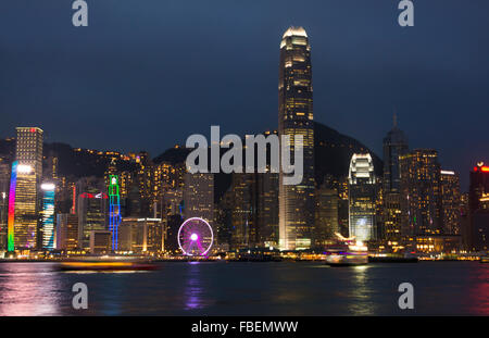 Chine Hong Kong skyline nuit harbour avec nouvelle roue de Ferris dans city skyscrapers et réflexions sur l'eau et de sommet de montagne dans la région de ba Banque D'Images
