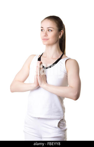 Portrait de jeunes sereine en modèle fitness sportswear blanc faisant du yoga pratique, mains dans Namaste, trois quarts vue, studio sh Banque D'Images