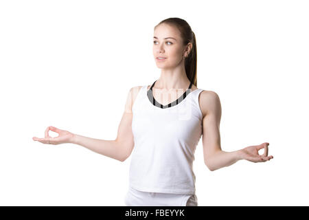 Portrait of smiling young beautiful girl in white sportswear faisant la pratique du yoga, les mains dans le yoga Gyan Mudra, geste trois quart Banque D'Images