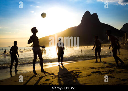 Rio de Janeiro, Brésil, silhouette d'habitants de jouer au ballon au coucher du soleil dans la plage d'Ipanema. Banque D'Images