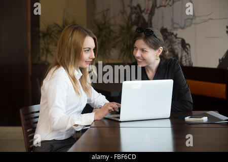 Deux jeunes femmes caucasiennes réunion d'amis, parler, assis à la table à côté de coffre Banque D'Images