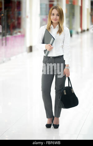 Portrait de l'employé de bureau, belle jeune femme en chemise blanche holding document noir dossier dans contemporary larg Banque D'Images