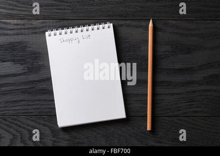 Liste de magasinage de phrase dans le bloc-notes sur la table en bois gris Banque D'Images