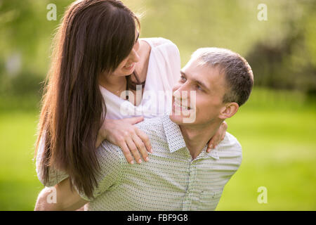 Portrait of happy young man and woman in love sur une date, petit ami de donner sa belle petite amie, smili piggyback ride ludique Banque D'Images
