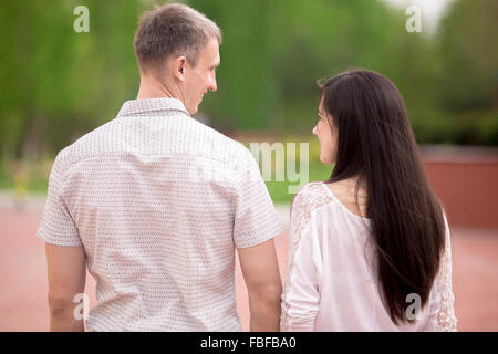 Couple d'amants, séduisant jeune homme et femme sur la date romantique, marcher main dans la main dans la région de park, parler et happy smiling, loo Banque D'Images