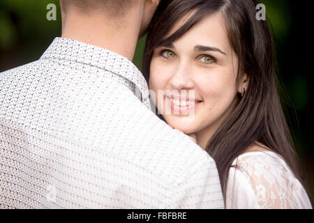 Portrait de jeune belle brunette happy smiling woman câlins avec son petit ami, se cachant derrière son épaule Banque D'Images