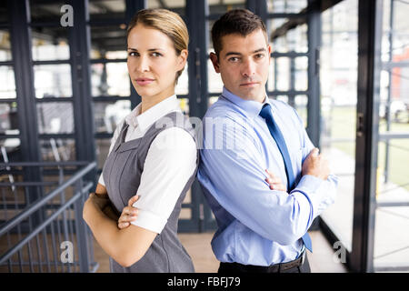 Les gens d'affaires standing back to back with arms crossed Banque D'Images