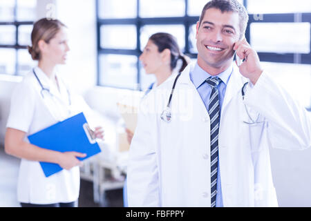 Smiling male doctor using smartphone Banque D'Images