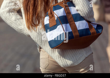 Jeune femme en chandail blanc avec sac à main sur l'épaule, mode de vie de rue Banque D'Images