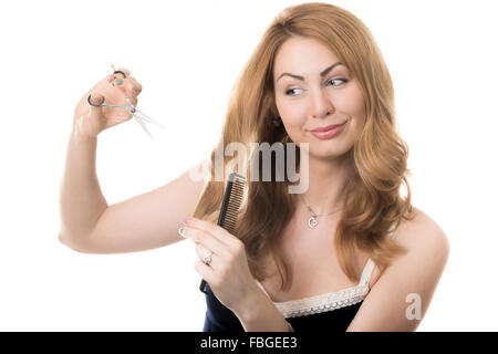 Funny portrait sur fond blanc de young attractive smiling blonde Caucasian woman holding coiffeur coiffure ciseaux et Banque D'Images