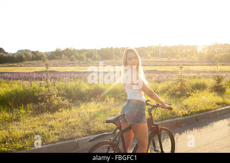 Portrait de la belle jeune femme à la recherche de nouveau assis sur vtt le port casual débardeur blanc et jeans shorts on countr Banque D'Images