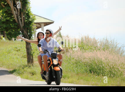 Couple heureux sur un scooter à les vacances d'été Banque D'Images