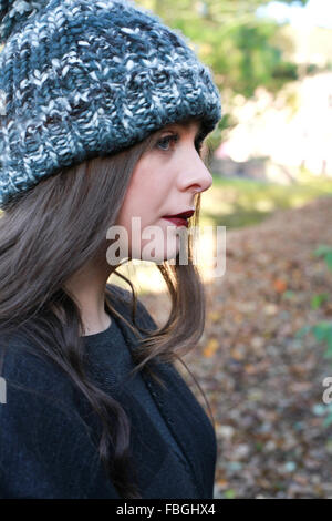 Profile of a Teenage girl wearing a pom pom hat au parc Banque D'Images