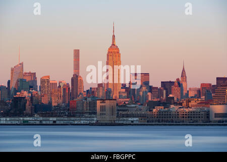 New York City Manhattan gratte-ciel au coucher du soleil de l'autre côté de la rivière Hudson. Au centre, l'Empire State Building. Banque D'Images