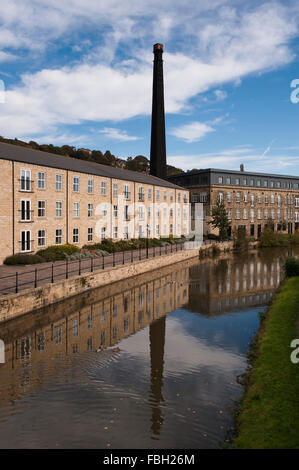 Quai, Britannia Leeds Liverpool Canal Bingley, Yorkshire, GB, UK - moulin avec haute cheminée (maintenant transformée en appartements) se reflète dans l'eau. Banque D'Images