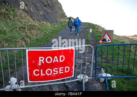 Les membres du public ne pas tenir compte de la "route fermée" à marcher leur chien ci-dessous Salisbury Crags malgré le risque de chutes de pierres. Banque D'Images