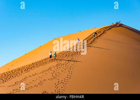 Escalade les touristes, des dunes de sable Sossusvlei, Désert du Namib, le parc de Namib Naukluft, Région Hardap, République de Namibie Banque D'Images