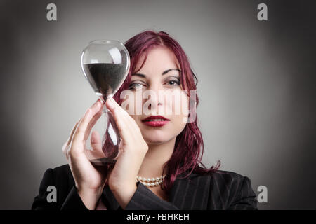 Portrait d'une femme en costume tenant une horloge de sable dans ses mains Banque D'Images