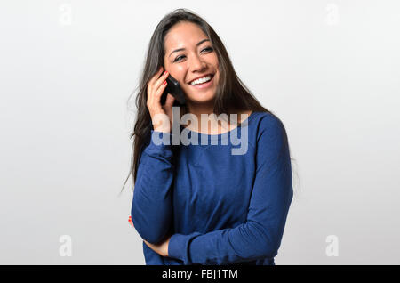 Laughing woman talking on a mobile phone smiling heureusement qu'elle écoute la conversation, haut du corps détendu Banque D'Images