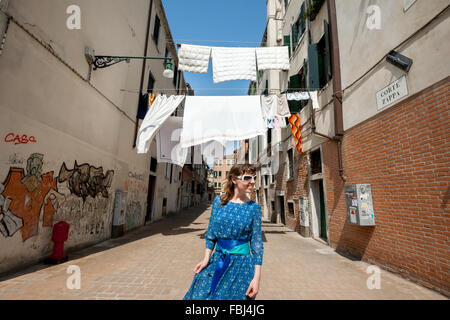 Happy smiling girl sur la promenade à Venise, sur l'arrière-plan blanc séchage blanchisserie entre les maisons sur backstreet étroit Banque D'Images