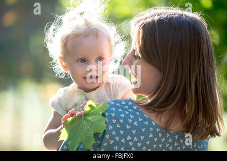 Portrait of happy young maman et adorable petite fille blonde, smiling mother holding sa petite fille dans les bras, parler, jouer à w Banque D'Images