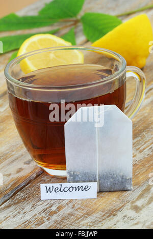 Carte de bienvenue avec un verre de thé et un sachet à thé appuyé contre elle Banque D'Images